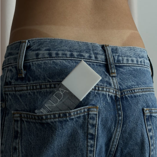 Person wearing blue jeans with a product labeled 'Nuda' in the back pocket.